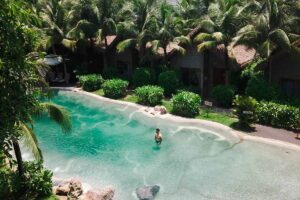 Bungalow resort sử dụng mái rơm nhân tạo bên hồ bơi tạo nên không gian nghỉ dưỡng đậm chất nhiệt đới
