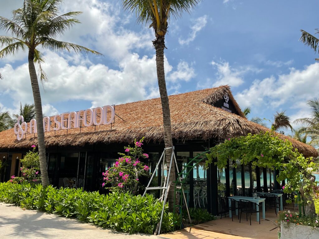  Không gian bên ngoài nhà hàng Ann Seafood với mái rơm nhân tạo và cảnh quan nhiệt đới