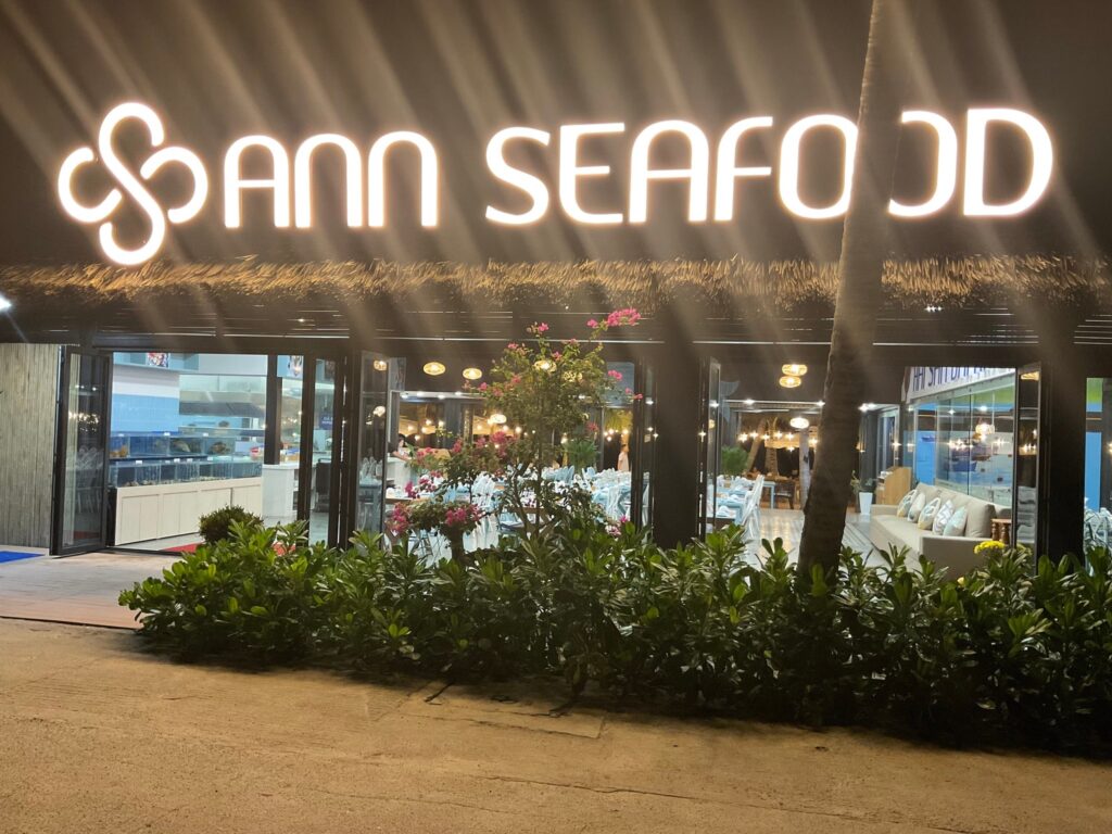 Biển hiệu Ann Seafood phát sáng nổi bật ban đêm dưới mái rơm nhân tạo