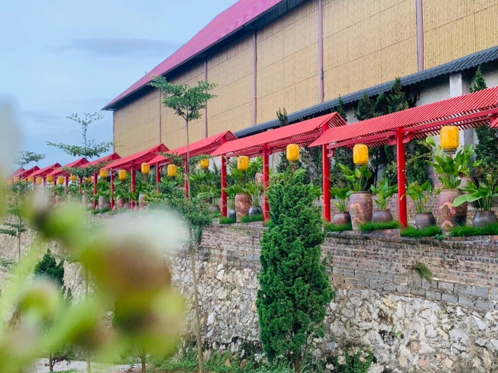 Mặt đứng công trình ốp tấm tre nhân tạo màu vàng, phối mái hiên đỏ truyền thống