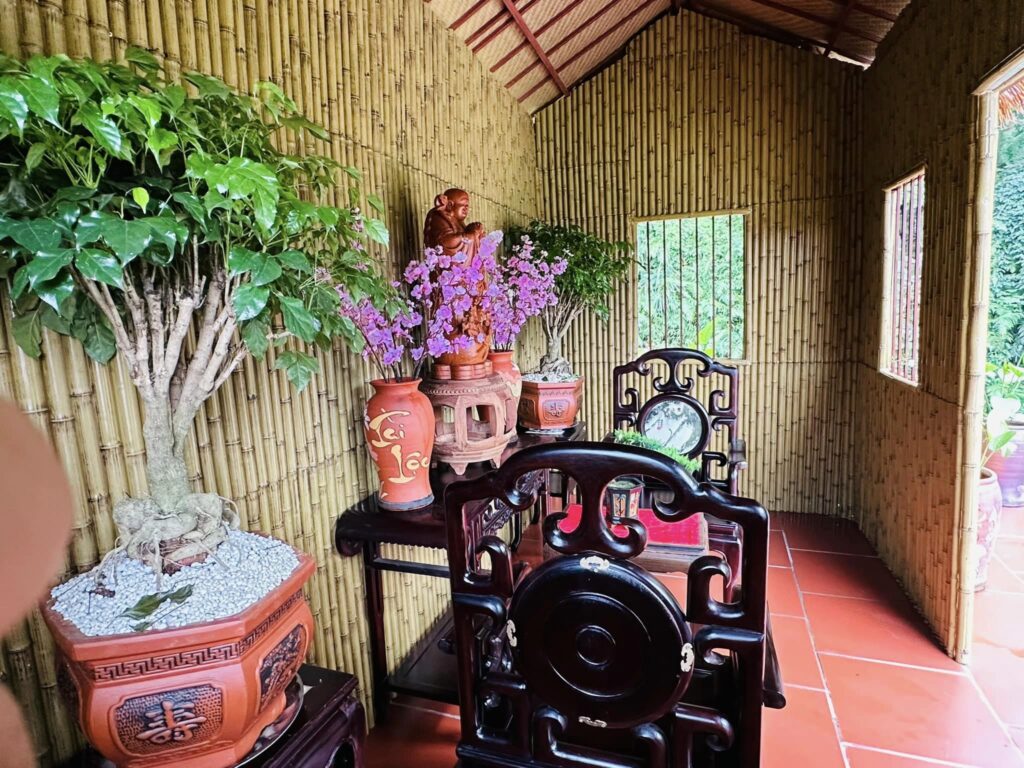 Bàn thờ đặt trong phòng ốp vách tre nhân tạo, phối bình sứ và cây xanh