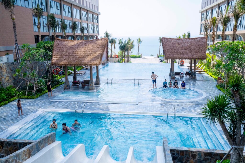 Hệ thống hồ bơi resort nổi bật với chòi nghỉ mái lá nhân tạo, vừa thẩm mỹ vừa chống nắng bền bỉ cho không gian ngoài trời.