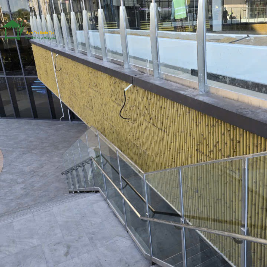 Góc cận cảnh mảng tường ốp tấm tre nhân tạo dưới cầu thang ngoài trời.