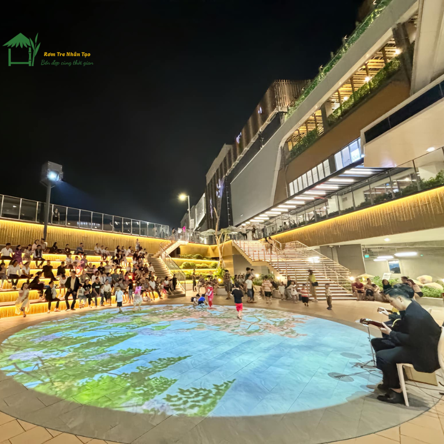 Không gian sân chơi ngoài trời tại Aeon Mall Huế vào buổi tối, nổi bật với hệ thống trang trí tấm tre nhân tạo.